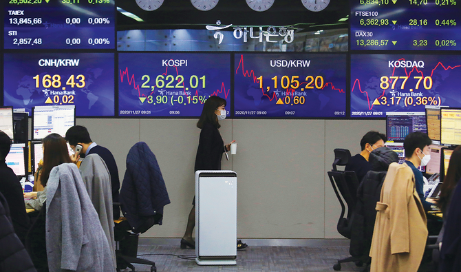 ソウルのKEBハナ・バンクの本店で、韓国総合株価指数を表示する画面の前を為替投機家が通り過ぎて行く。（AP）
