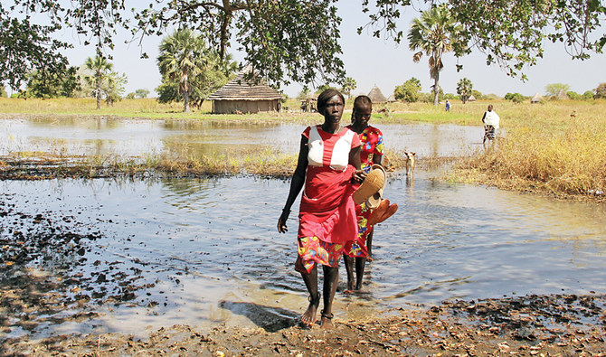 11月27日、南スーダンのマナゲル・アジャク村で浸水した地域を渡る避難民の女性（ロイター通信）