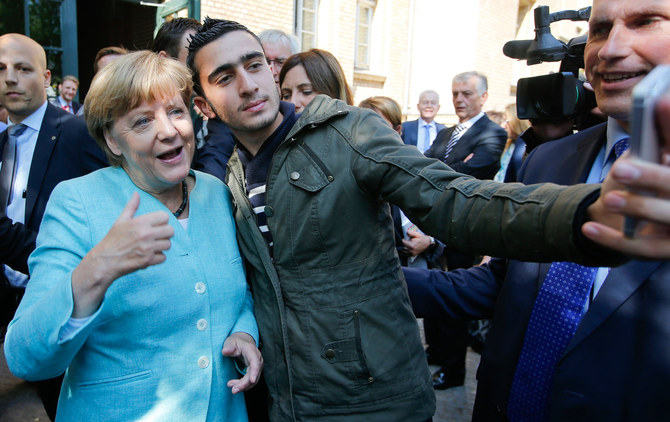 ベルリンのシュパンダウ地区にある難民キャンプの外で、アンゲラ・メルケル首相と自撮りする移住者。(ロイター通信)