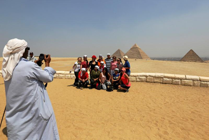 エジプト、カイロ郊外のギザの大ピラミッドの前で記念写真を撮る観光客。（ロイター／ファイル）