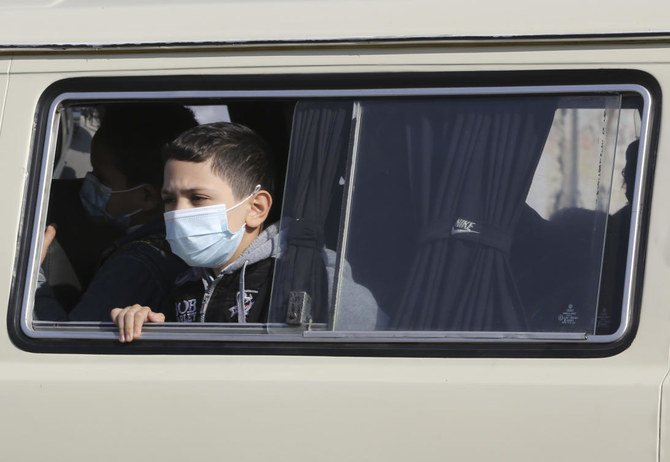 ガザ市で子どもたちが家に帰る中、COVID-19新型コロナウイルスの大流行のためにマスクをつけ、スクールバスの窓から外を見るパレスチナ人の少年、2020年12月3日。（AFP通信）