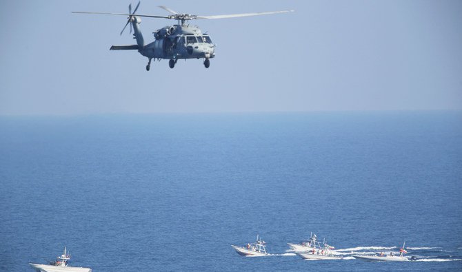 イランの核開発計画で緊張が高まる中、ホルムズ海峡で革命防衛隊の巡視船の上空を飛行する米軍のSH-60B シーホークヘリコプター。 （AP通信）