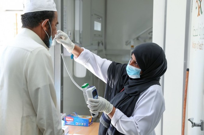 サルマーン国王の指示に基づき、最大のコロナウィルスワクチン作戦が木曜に始まった。上の写真は移動クリニックで患者の体温をチェックする看護師。2020年4月7日撮影。（AFP）