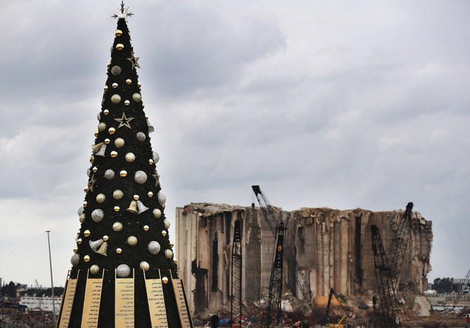 2020年12月23日水曜日、レバノンのベイルートで、8月にベイルート港で起きた爆発事故で亡くなった人々の名前を飾り付けたクリスマスツリーが、損傷したサイロの前に展示されている。（AP）