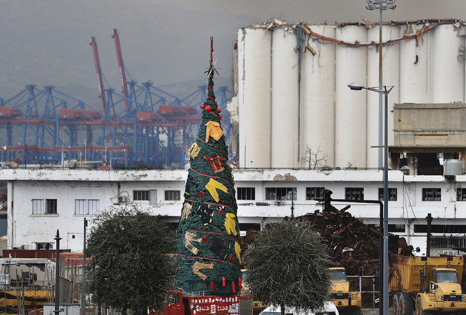 2020年12月22日火曜日、レバノンのベイルートで、8月にベイルート港で起きた爆発事故で消火活動に当たって死亡した人々をしのび、消防士の制服を飾り付けたクリスマスツリーが、損傷したサイロの前に展示されている。（AP）