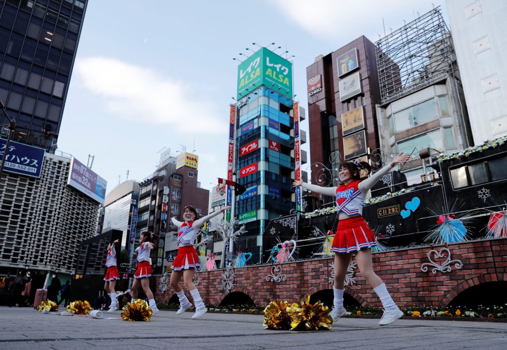 2021年1月7日、新型コロナウィルス感染拡大の中、フェイスシールドを付けたチアリーダーたちが、日本の東京、新橋駅前で通勤時間中に人々を元気づけるためダンスをする。(ロイター)