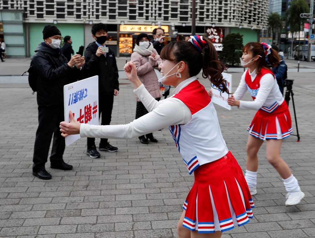 2021年1月7日、新型コロナウィルス感染拡大の中、フェイスシールドを付けたチアリーダーたちが、日本の東京、新橋駅前で通勤時間中に人々を元気づける。(ロイター)