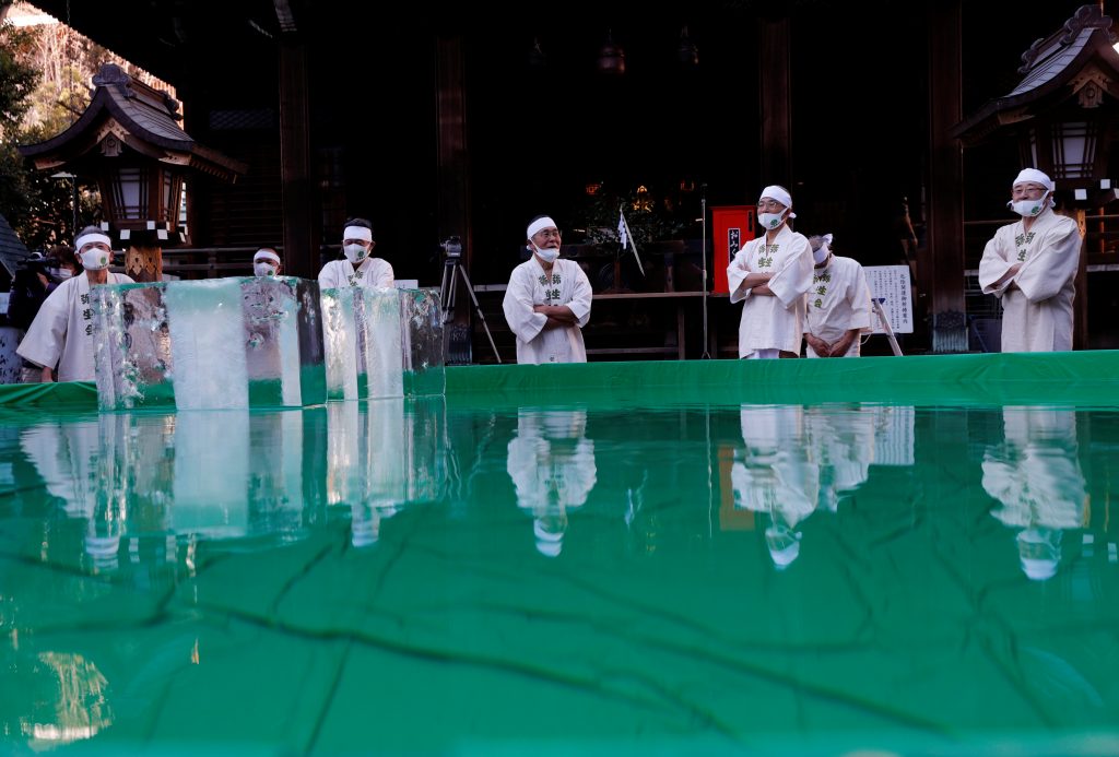 コロナウィルス伝染病（COVID-19）が蔓延する中、東京の鐵砲洲稲荷神社の儀式で魂を清めパンデミックの克服を願うため、氷水の風呂に浸かる準備をする保護マスクを着けた参加者たち。2021年1月10日撮影。ロイター/キム・ギョンフン