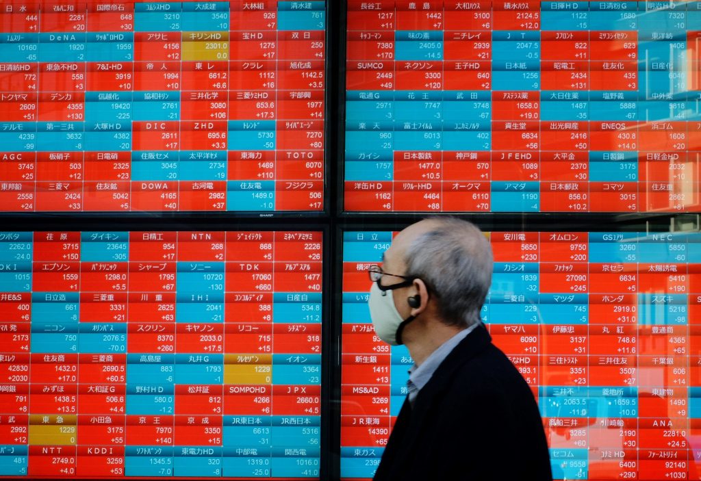 2021年1月13日に東京の東京証券取引所で企業の株価を表示する電子相場表示板を見つめる歩行者。（AFP）