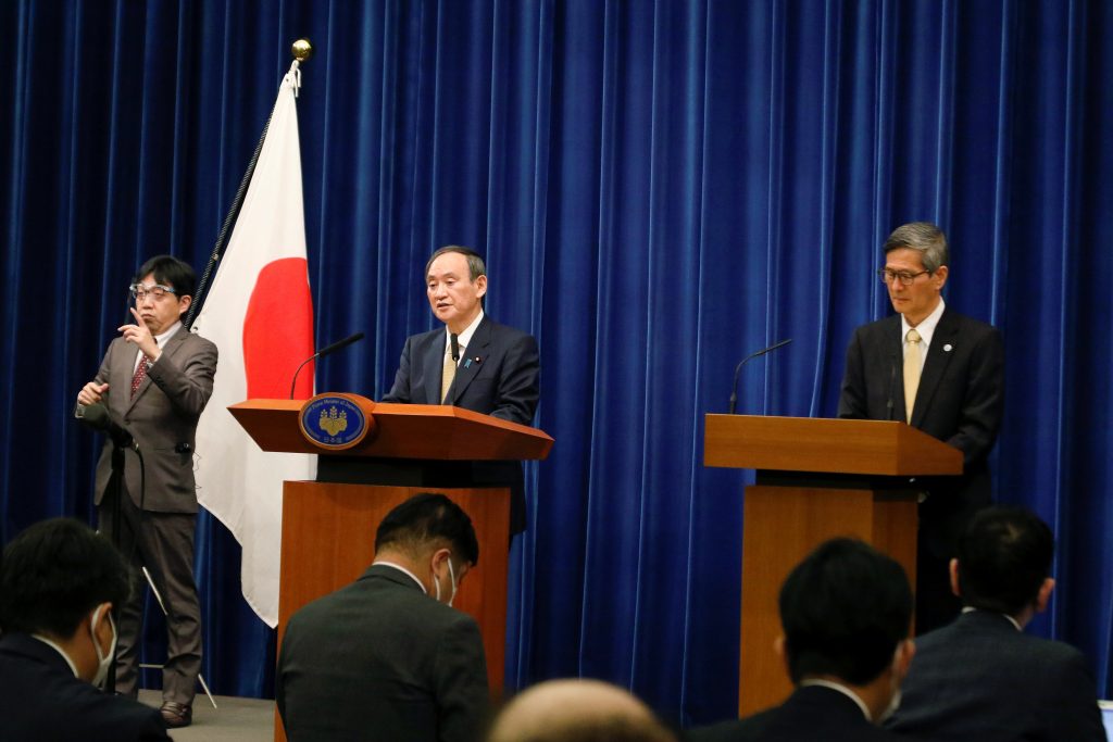 2021年1月13日、東京の首相官邸で行われた記者会見にて、地域医療機能推進機構の尾身茂理事長の隣りで話す菅義偉首相。（ファイル写真 / ロイター）