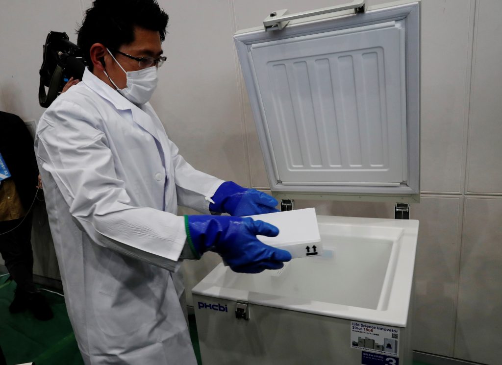 2021年1月27日、日本がコロナウイルスワクチン接種キャンペーンの準備をするなか、東京南部の川崎の大学の体育館で、模擬接種訓練中に医薬品冷蔵庫から水が入ったバイアルを取り出すスタッフ。（ファイル写真/ロイター）