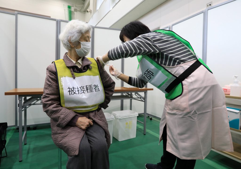 2021年1月27日、日本がコロナウイルスワクチン接種キャンペーンの準備をするなか、東京南部の川崎の大学の体育館で、模擬接種訓練中に医薬品冷蔵庫から水が入ったバイアルを取り出すスタッフ。（ファイル写真/ロイター） 