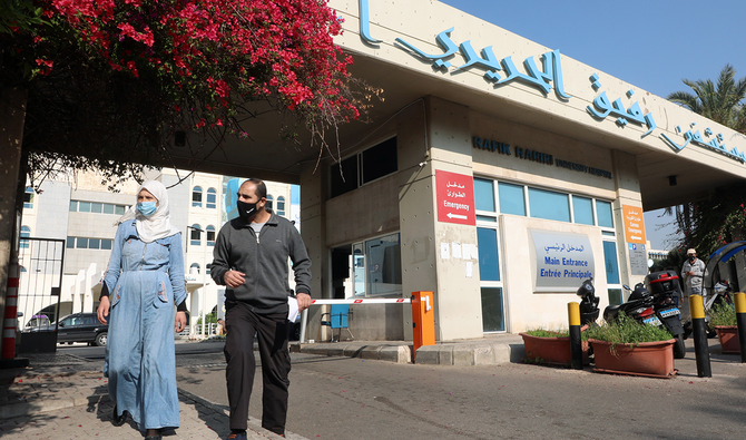 新型コロナウイルス感染症（COVID-19）のパンデミックが懸念される中、防護マスクを着用した人々がラフィク・ハリリ大学病院の外を歩く。ベイルート、レバノン、2021年1月4日 (ロイター)