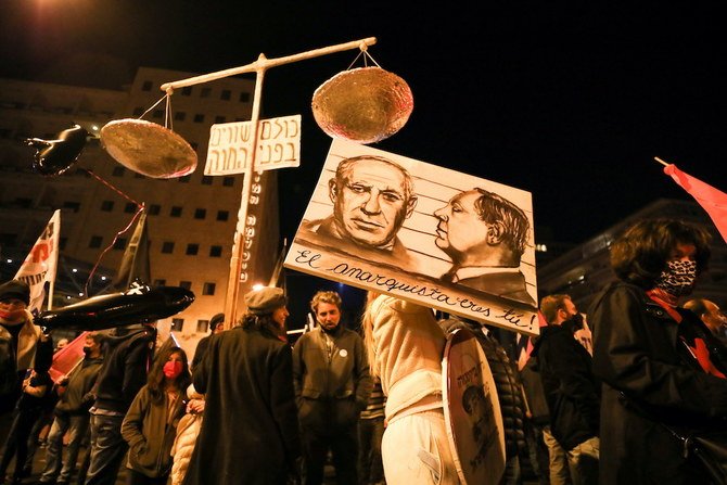 2021年1月9日にエルサレムで、人々がベンヤミン・ネタニヤフ首相の汚職容疑とコロナ危機対策の処し方に対する抗議デモに参加している。ボードの絵には「アナーキストはお前だ」と書かれている。（ロイター）