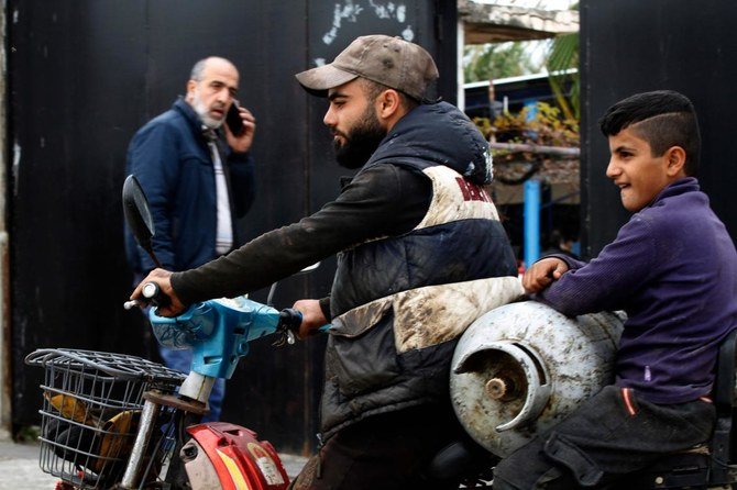 レバノンの人々がCOVID-19の蔓延による全面的ロックダウンの1日前に食料の備蓄を急ぐ中、バイクに乗った男性がガスボンベを運んでいる。（2021年1月13日、レバノン南部の都市シドンで撮影）（AFP通信）