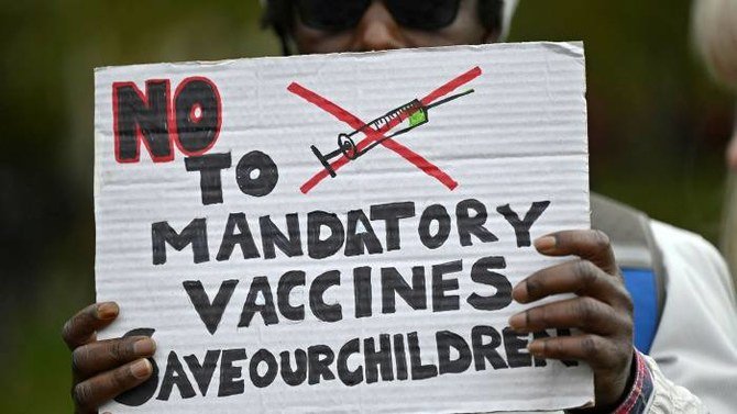 10月にロンドンで行われた予防接種の義務化に反対するデモでプラカードを掲げる抗議者。カナダの有力なイスラム学者は、コロナウイルスワクチンに関する陰謀論を信じてはいけないと警告。(AFP/File Photo)