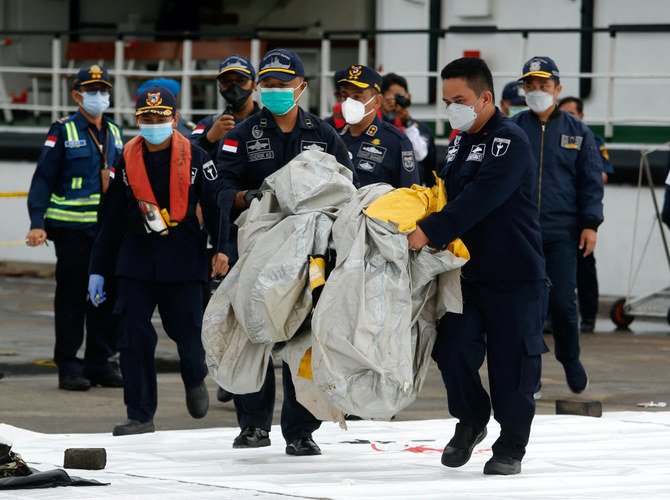 インドネシアの捜索救助隊員が、日曜日、2021年1月9日に海に墜落したスリウィジャヤ航空機SJ182便の残骸と思われるものを運ぶ。 (Reuters)