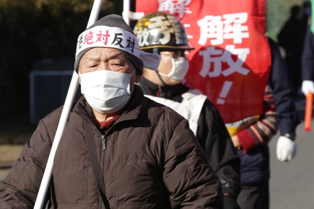 成田空港近くの土地から立ち退きを命じられた裁判所の命令に抗議するため、市東孝雄さんが旗を掲げている。(ANJ photo)