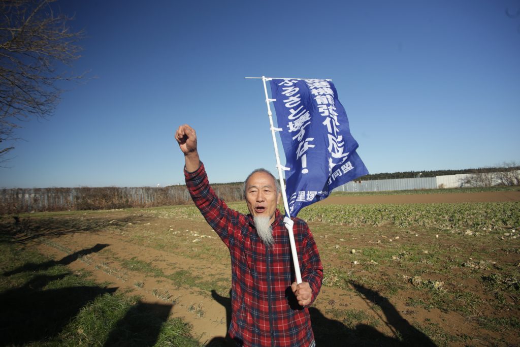 連帯を示すため、市東さん陣営で拳を上げる高齢の男性。(ANJ photo)