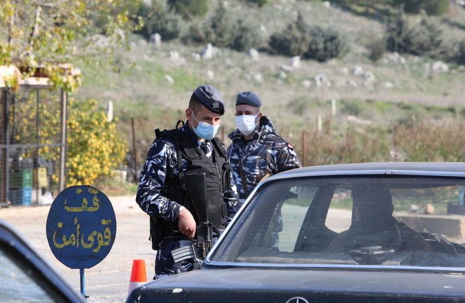 レバノンでは新型コロナウイルスの感染増加を防ぐため、3週間の完全なロックダウンを公表した。マスクをした警察官が検問所で運転手と話している。レバノン南部・マルジャヨーンにて（写真/ロイター）