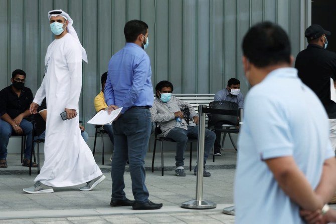UAE、アブダビのクリーブランドクリニック病院で、防護マスクを着用した病院職員が新型コロナウイルスの検査を受けるために並んでいる人々を見守っている。（ロイター通信／資料写真）
