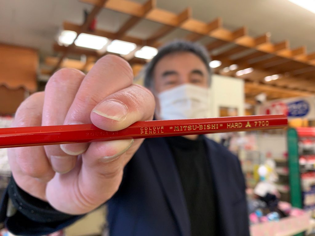 三菱鉛筆を手に持つ東京の文具店、相馬屋源四郎商店の11代目店主、長妻直哉さん(2021年2月3日、ロイター/Chang-Ran Kim)