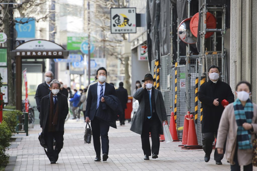 2021年2月10日水曜日、コロナウイルス感染拡大予防のためフェイスマスクを着けた人々が東京の街中を歩く。（AP写真/ササハラコウジ） 