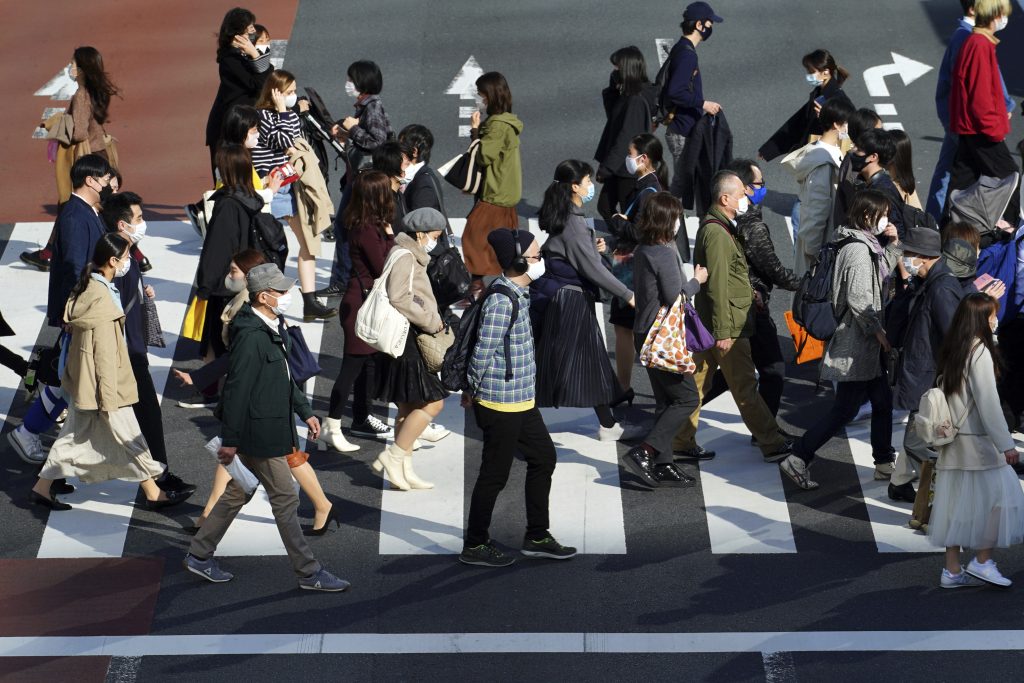 新型コロナウイルスの感染拡大を抑えるために保護マスクを着用した人々が横断歩道を歩く2021年2月22日（月）、東京都内。日本の首都では月曜日に170人以上の新たな新型コロナウイルス感染者が確認された。(AP)