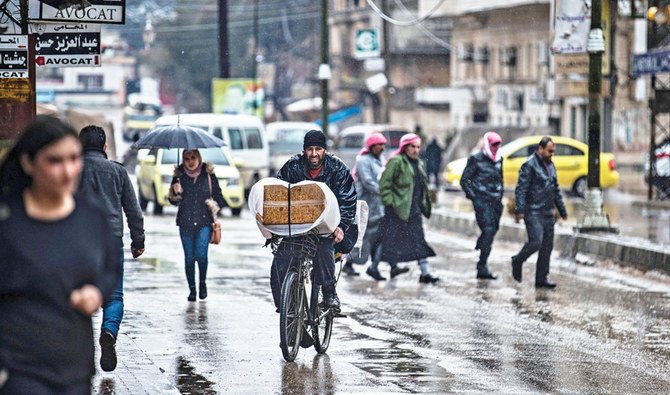 シリア北東部のクルド人が大半を占めるカーミシュリー市では、店が閉まっている中、日常生活を送る人がいる。体制寄りの抗議者との緊張が高まる最中のことである。(AFP)