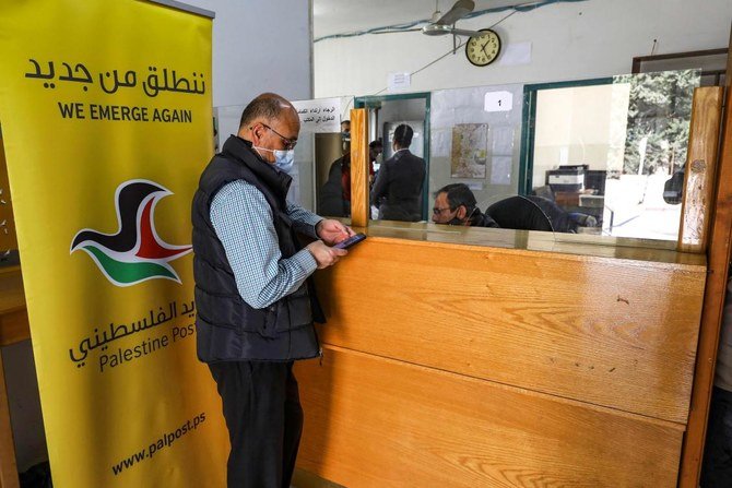 2021年2月7日、占領下のヨルダン川西岸地区エルサレムから北に約15キロ離れたアル・ビレ市の郵便局にて郵便局員の手伝いをする男性。(AFP)