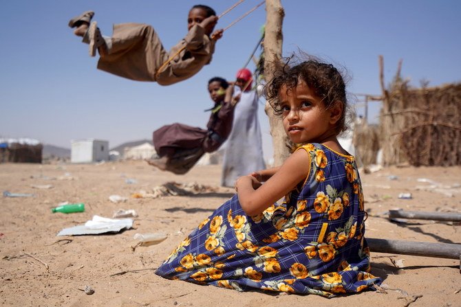 2月16日、イエメン・マリブの国内避難民キャンプで、他の子どもたちがブランコで遊ぶ中、座っている少女。（ロイター通信）