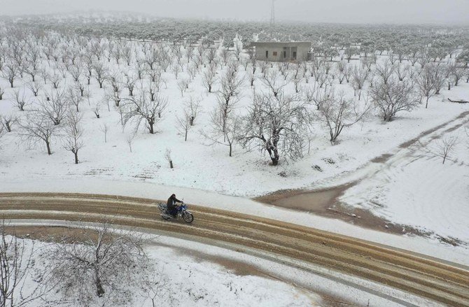 2021年2月17日、シリアのイドリブ県の、反体制派が支配する北部の田舎にあるジャバル・ザーウィヤ地域で、雪に覆われた森の中をシリア人男性がバイクで走っている。（AFP）