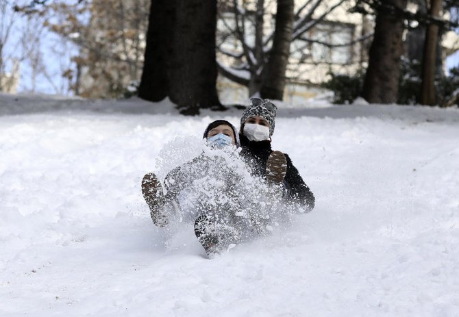 2021年2月17日水曜日 、トルコのアンカラにある、雪に覆われたSeymenler ParkでAysegul Cepogluさん（後ろ）とAhmet Efe Isikさんが丘を滑り降りている。（AP）