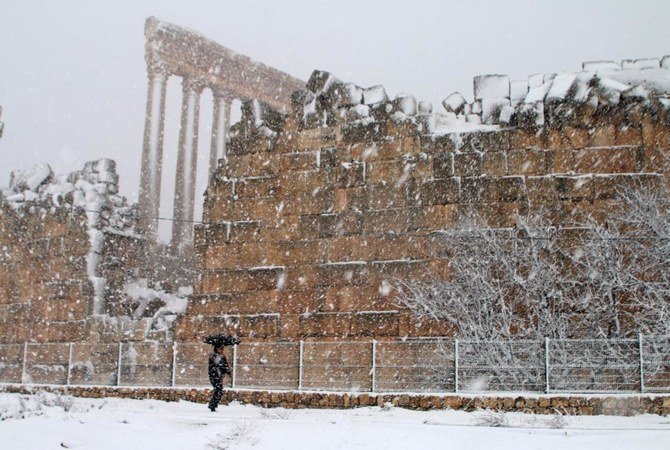 2021年2月17日、レバノン東部ベカー高原で雪が降る中、男性がバールベックの古代遺跡に沿って歩いている。（AFP）