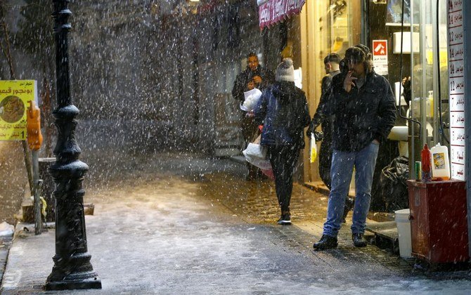 2021年2月17日、ヨルダン川西岸の都市ラマラで雪が降る中、人々が通りを歩いている。(AFP)