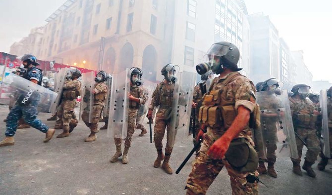 大規模な科学爆発の後、ベイルート中心部の国民議会議事堂付近での昨年8月の抗議集会の最中に、レバノンの治安部隊が集まっている。〔資料／AFP通信〕