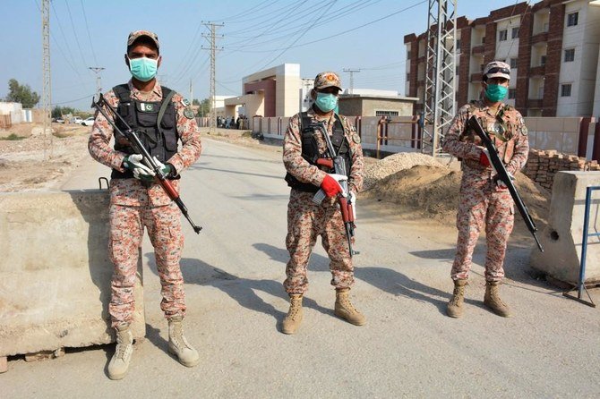 パキスタンとイランの国境の町タフタンから戻ってくる人々の隔離施設へ続く道路で、兵士が警備に立つ。(AFPファイル写真)