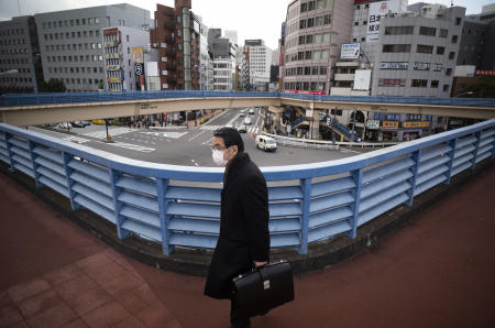 2021年2月18日(木)、東京の歩行者用陸橋をフェイスマスクを着用した男性が歩きます。(AP)