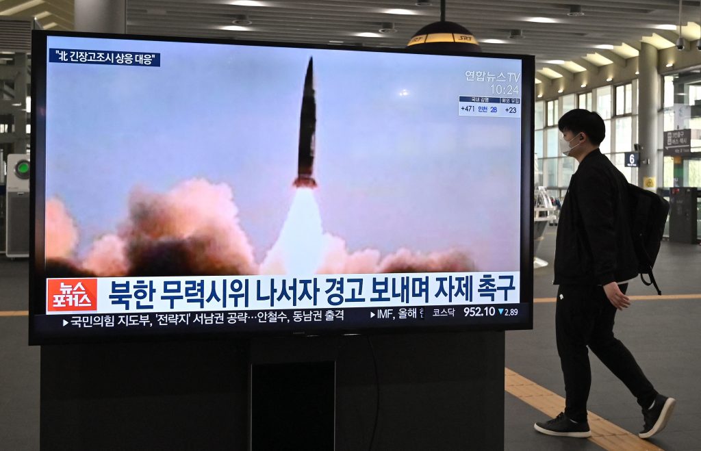 2021年3月25日に撮影されたこの写真には、ソウルの水西駅のテレビ画面の前を通り過ぎる男性とともに、北朝鮮が行なった直近の戦術的誘導ミサイル発射実験のニュース映像が映されている。 （AFP）