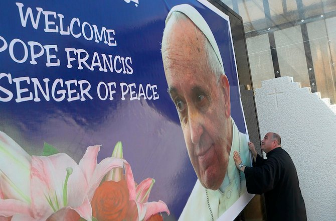 教皇の訪問に備えて、フランシスコ教皇を歓迎するポスターをバグダッドの聖ヨセフカルデア教会に貼るナディール・ダコ神父（AP通信）