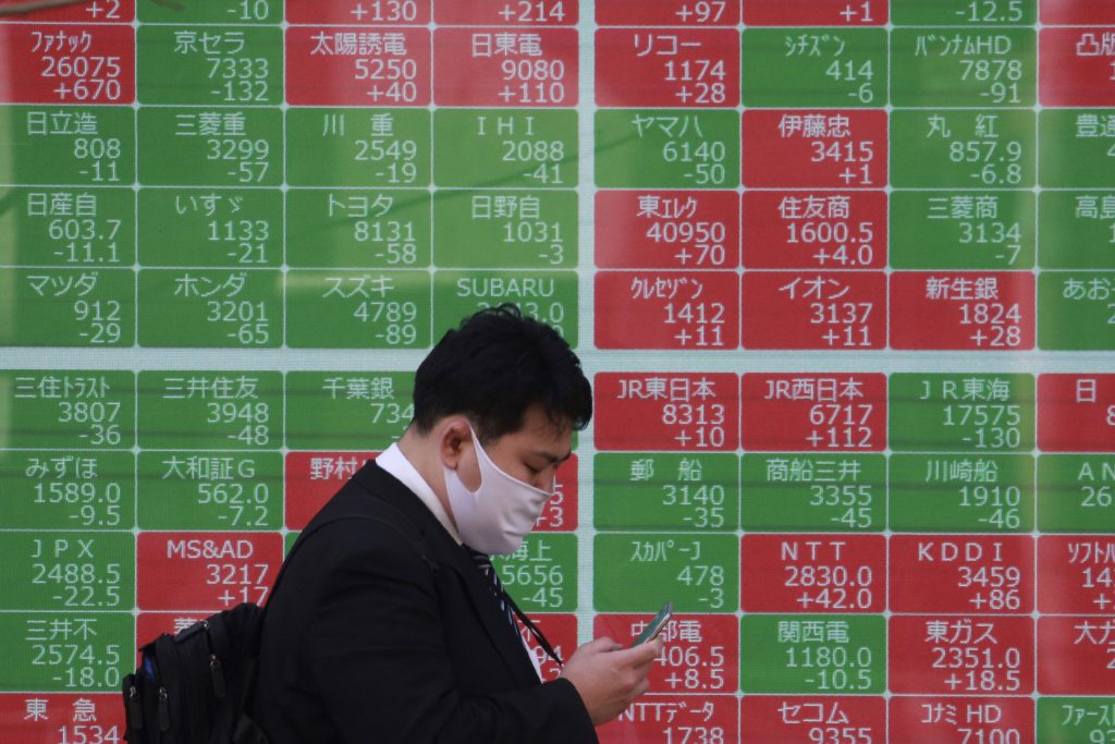 2021年3月10日、東京の証券会社の電光掲示板前を歩行する男性(File Photo/AP)