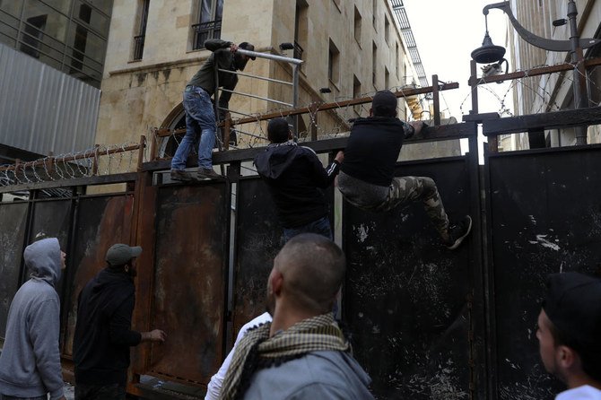2021年3月13日（土）、レバノンのベイルートで行われた抗議活動で、デモ参加者が国会の建物にたどり着くのを防ぐために治安部隊が設置した金属製の壁を登る反政府デモの参加者。（AP通信）