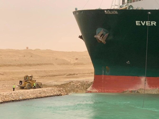 スエズ運河で強風に煽られて座礁したコンテナ船の横にいる作業員。（ロイター通信）