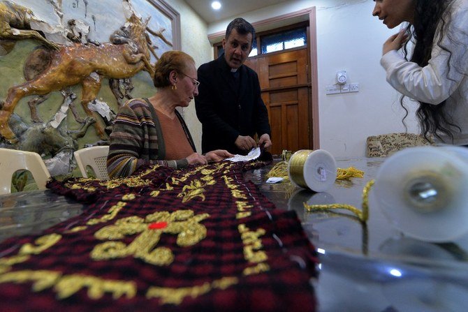 フランシスコ教皇のニーナワー県のカラコシ訪問中、カルジヤ・バクタルが教皇に贈るために金糸を使って貴重な祈りのショールを刺繍している様子を見ているイラク人司祭アマル・ヤコ。（AFP通信）