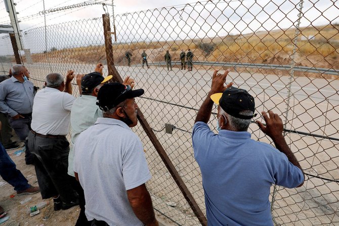 イスラエルに渡れなかった通勤中のパレスチナ人労働者は、イスラエル占領下の西岸のヘブロンの近くで閉鎖された検問所の近くの柵のそばに立っている(ファイル / ロイター)