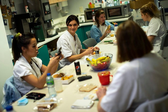 看護婦のアン-キャサリン・シャルリエ（中央）は、ベルギーのリエージュにあるCHRシタデル病院の新型コロナウイルス感染症集中治療棟で晩ご飯の休憩中に同僚に話しかけている。（写真提供/AP）