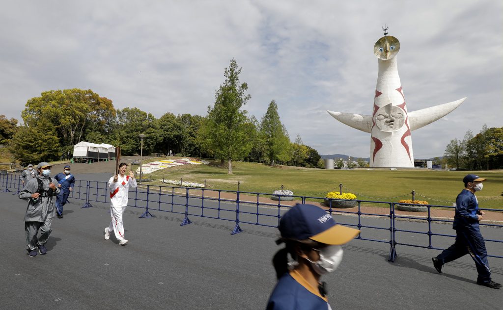 一般観客の立ち入りが制限された万博記念公園内で、聖火を手に走る競泳五輪銅メダリストの寺川綾さん＝１３日午前、大阪府吹田市 (AFP)