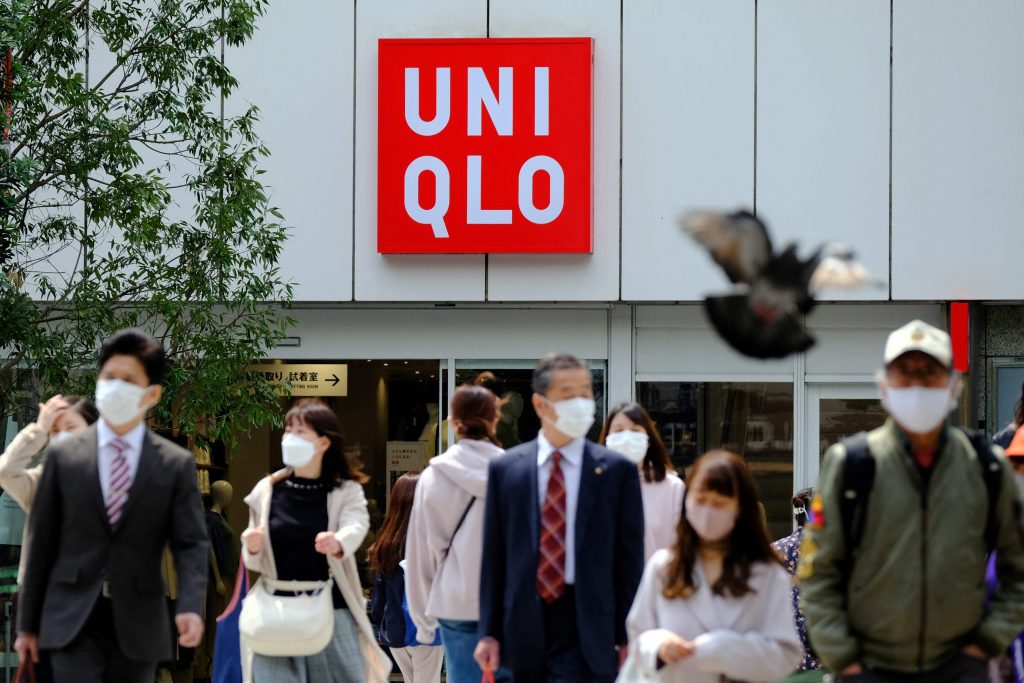 2021年4月8日、東京で日本のファーストリテイリングが運営する衣料品店ユニクロの前を歩いていく人々。（AFP）