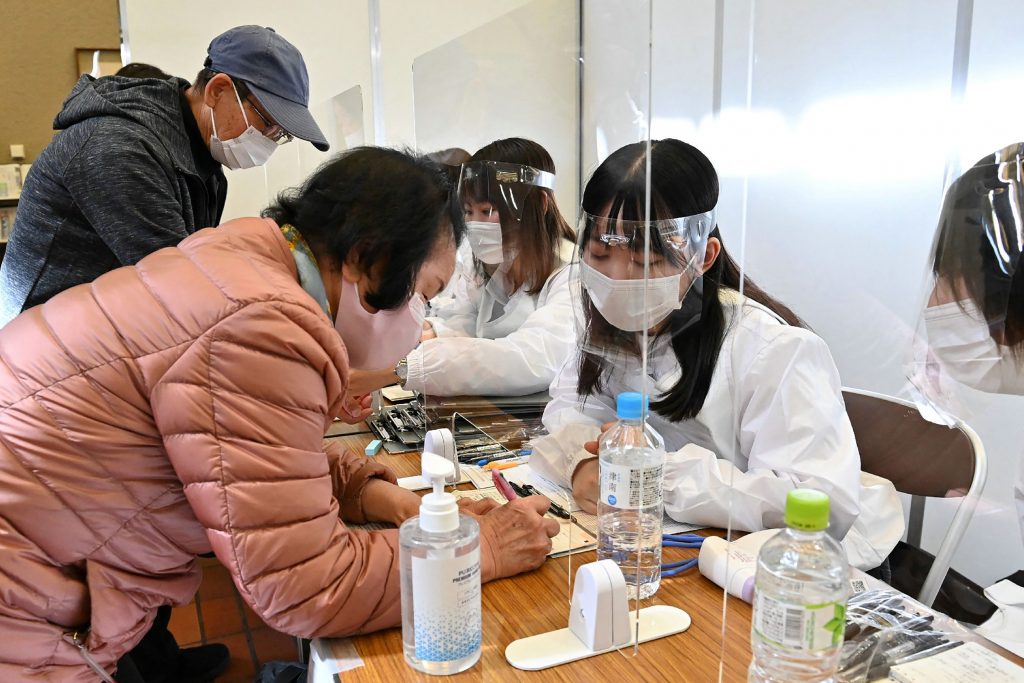 2021年4月12日、日本が高齢者へのワクチン接種を開始するにあたり、東京都八王子市でCOVID-19ワクチンの接種を受けるために登録する高齢者。(AFP、時事通信提供)