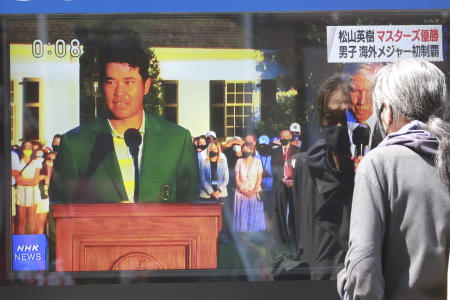 日本のゴルファー、松山英樹がマスターズ優勝後にコメントする様子を報道するテレビニュースを通行人が観ている。（AP）